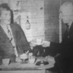 Luke (played by M. McGee) serves coffee to Det.-Sergeant Harris (played by F.C. Wheeler)